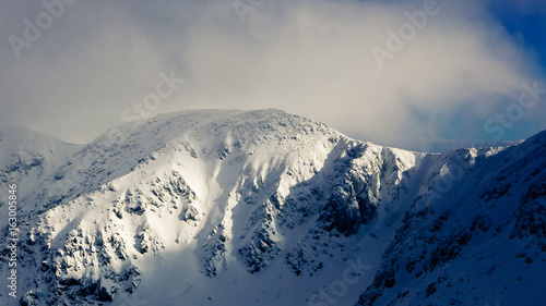 Peaks and ridges of mountains in cloudy and partly clear sky at winter.