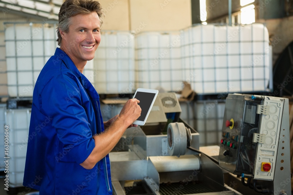 Smiling worker using digital tablet in factory Smiling worker using digital tablet in factory