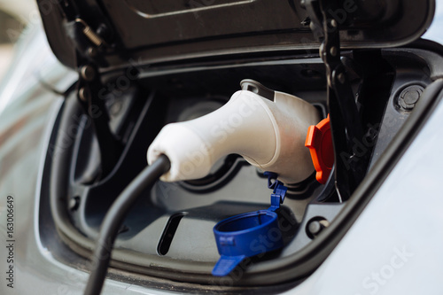 White electrical nozzle being plugged into e-car