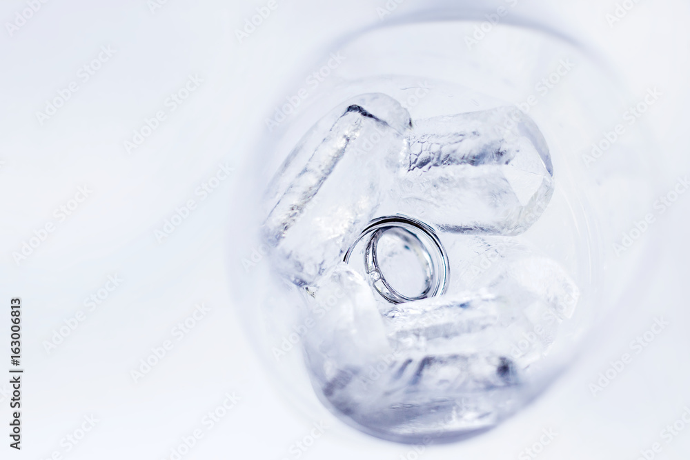 Pair of golden wedding rings with diamond in glass of ice cubs. Symbol of love, marriage or cooling of relations. Pair of golden wedding rings with diamond in glass of ice cubs. Symbol of love, marriage or cooling of relations.