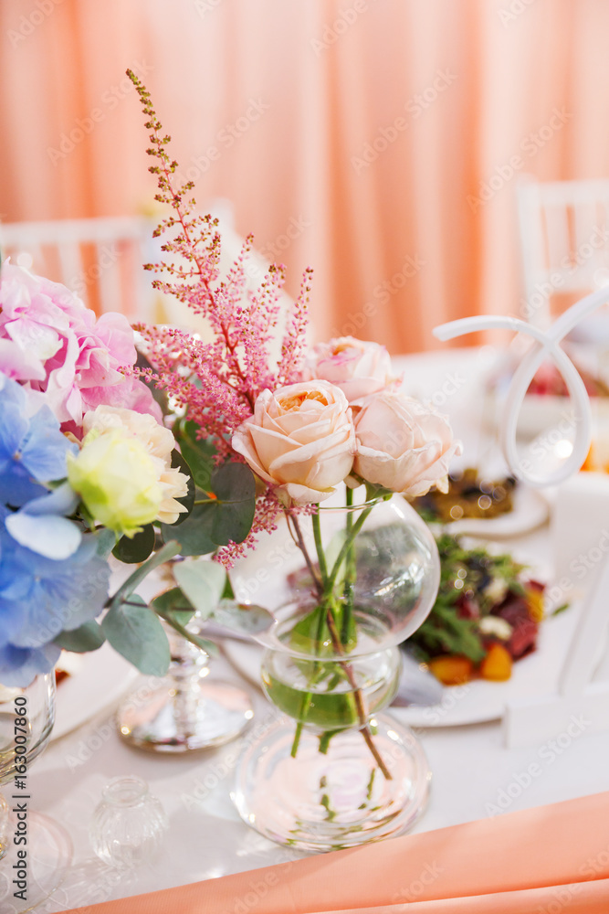 Table set for wedding banquet with floral composition of roses and astilbe. Flower decoration in vase. Table set for wedding banquet with floral composition of roses and astilbe. Flower decoration in vase.