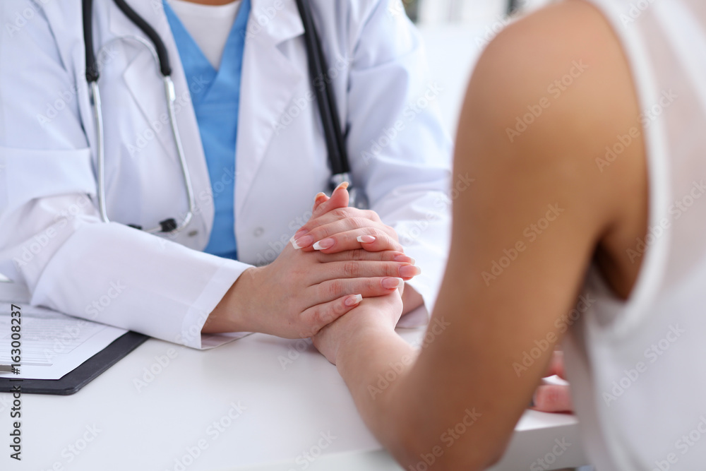 Naklejka premium Close up of doctor hands reassuring her female patient