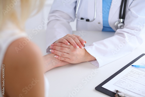 Close up of doctor hands reassuring her female patient