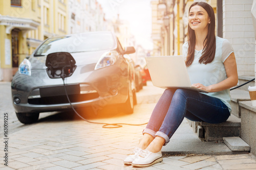 Φωτογραφία Upbeat woman working on laptop while waiting for car