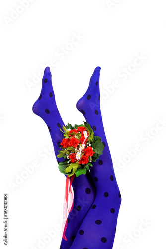  A flower bouquet is held up high by a woman's feet wearing blue polka dot nylon stockings. 