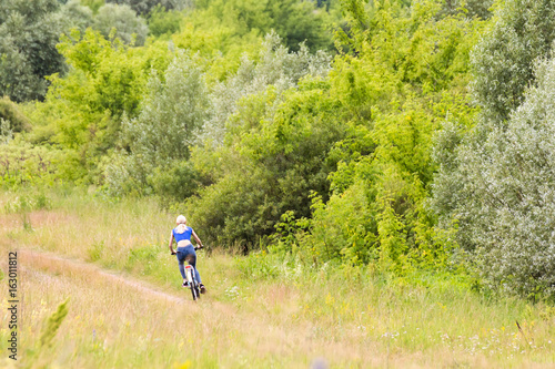 blonde girl riding bicycle summer day in field