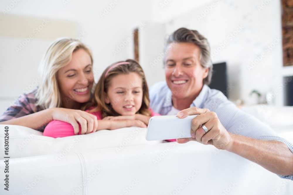 Happy family taking selfie on mobile phone in living room Happy family taking selfie on mobile phone in living room