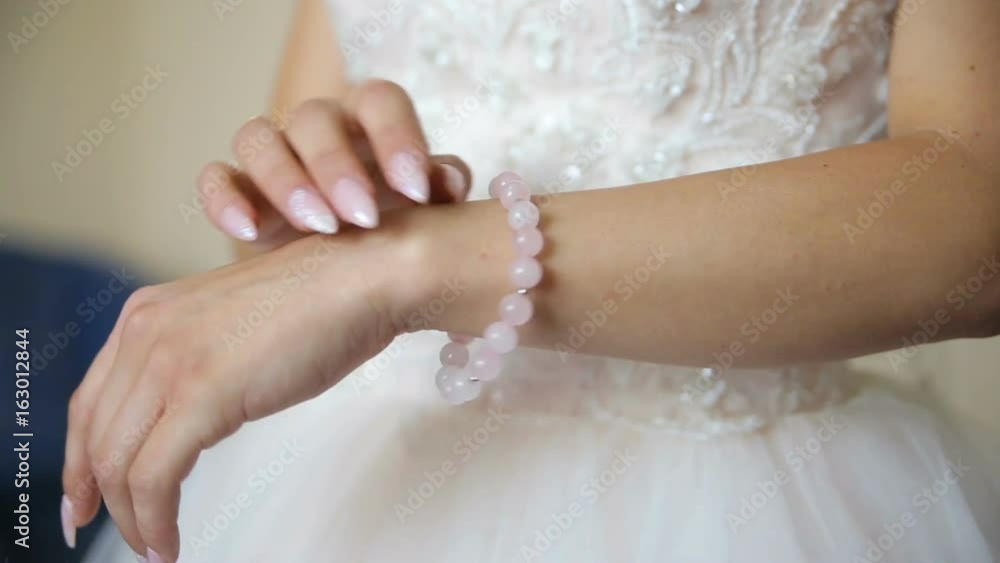 The bride puts the necklace on her arm The bride puts the necklace on her arm