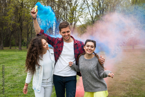 Young friends firing colourful smoke torches