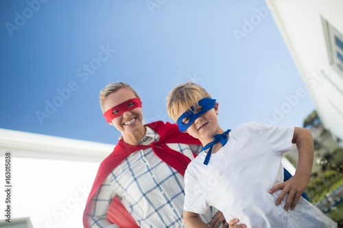 Smiling mother and son pretending to be superhero in garden