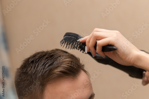 close up of female hairdresser drying her male customer's hair in her hairdressing salon