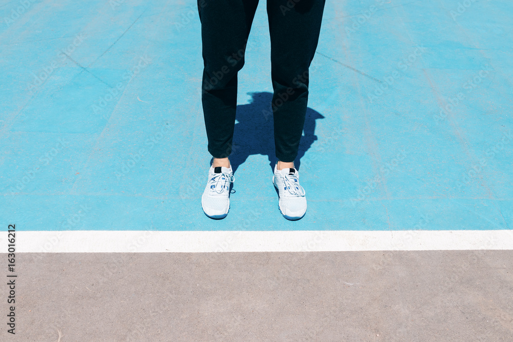 Φωτογραφία Cropped image of female legs in sneakers and black pants are on a blue sports fi