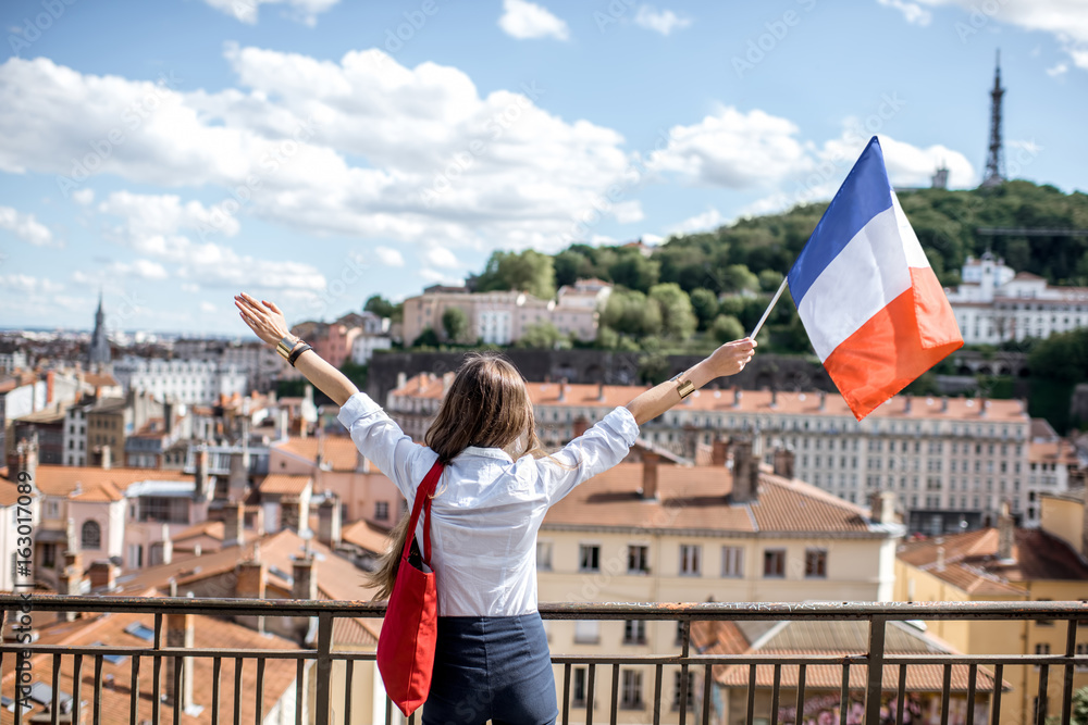 Φωτογραφία Young woman holding a french flag on the city background in Lyon old town in Fra