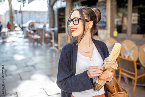 Young stylish woman buying a french baguette standing on the street in Lyon city