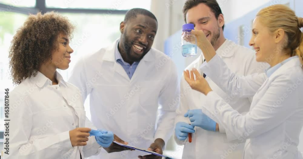 Mix Race Scientists Team Discuss Liquid In Bottle Happy Smiling Reseachers Working Together On Experiment In Laboratory Slow Motion 60 Mix Race Scientists Team Discuss Liquid In Bottle Happy Smiling Reseachers Working Together On Experiment In Laboratory Slow Motion 60