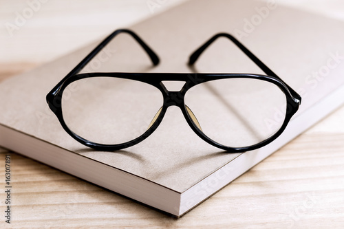Glasses and book on wooden table.