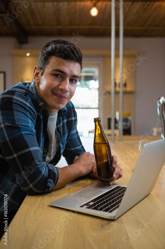 Portrait of man with laptop enjoying beer