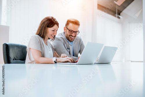 Group of confident business partners working with laptop in office photo