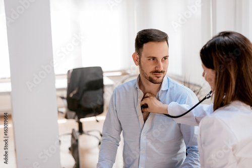 Doctor examining male patient in hospital with sthetoscope