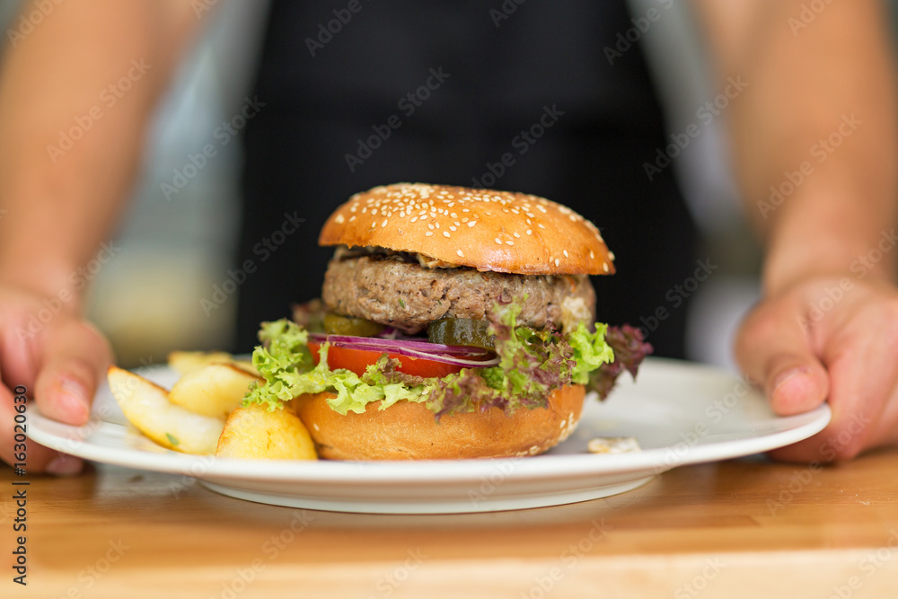 Waiter serves hamburger on a plate
Waiter serves hamburger on a plate