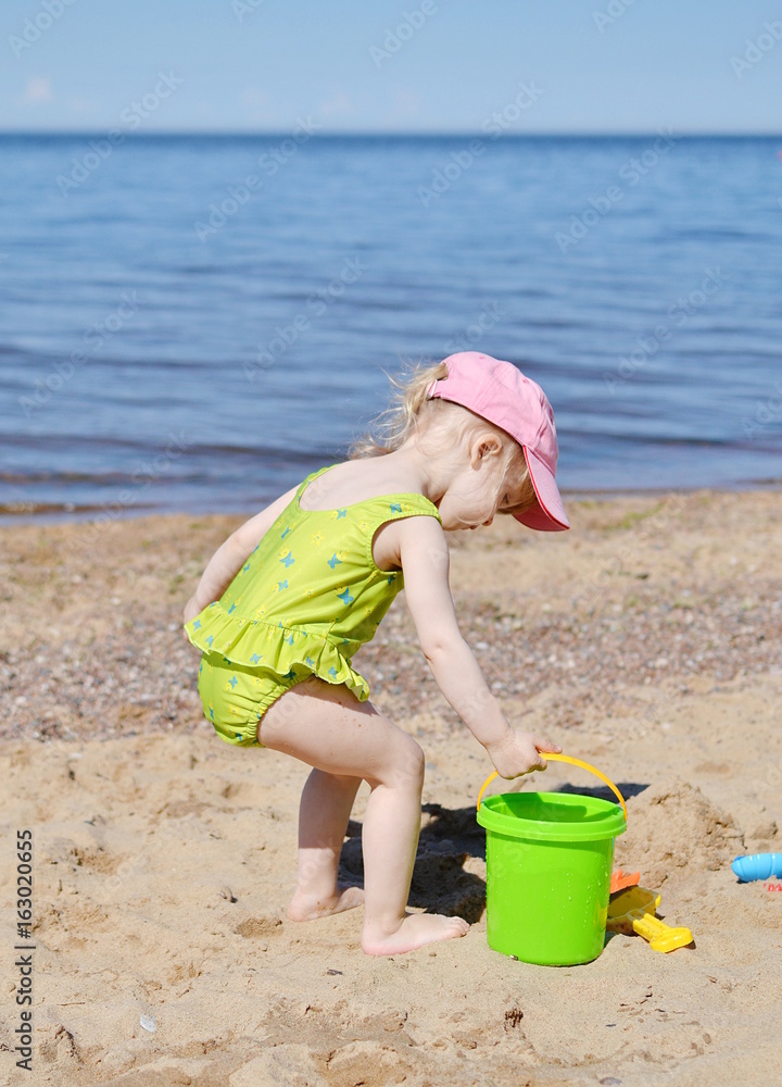 Little girl playing at the beach in sunny day Little girl playing at the beach in sunny day