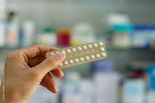 Fototapeta Naklejka Na Ścianę i Meble -  birth control pills in hand with blurred medicine bottle background .oral contraception concept.