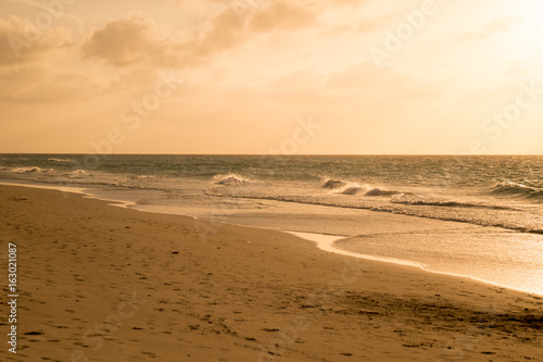 Fototapeta Naklejka Na Ścianę i Meble -  Golden sand of azure calm Caribbean sea shore with waves in summer sunset time