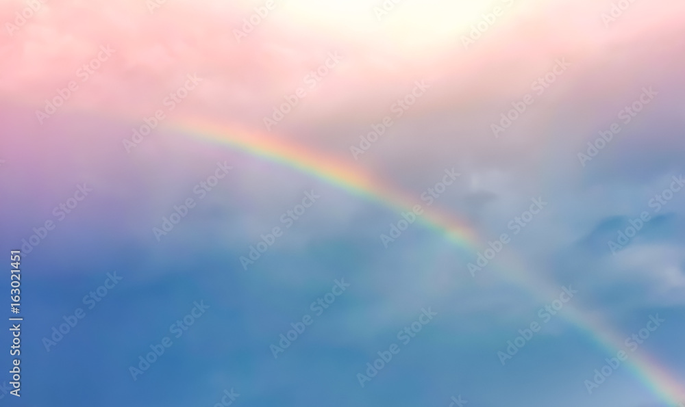 Blur and haze blue and pink pastel sky  with rainbow over the cloud after raining day with sunbeam