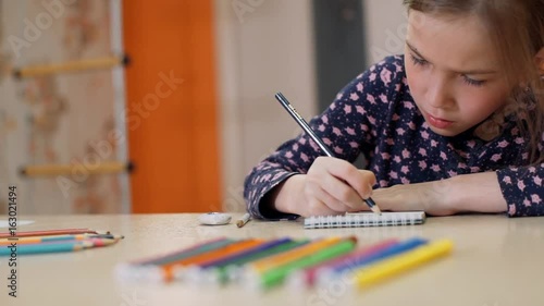 Little girl with a pencil makes a sketch in a notebook photo