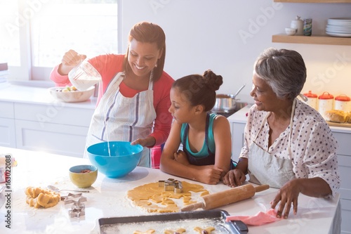 Happy multi-generation family preparing cookies in kitchen
