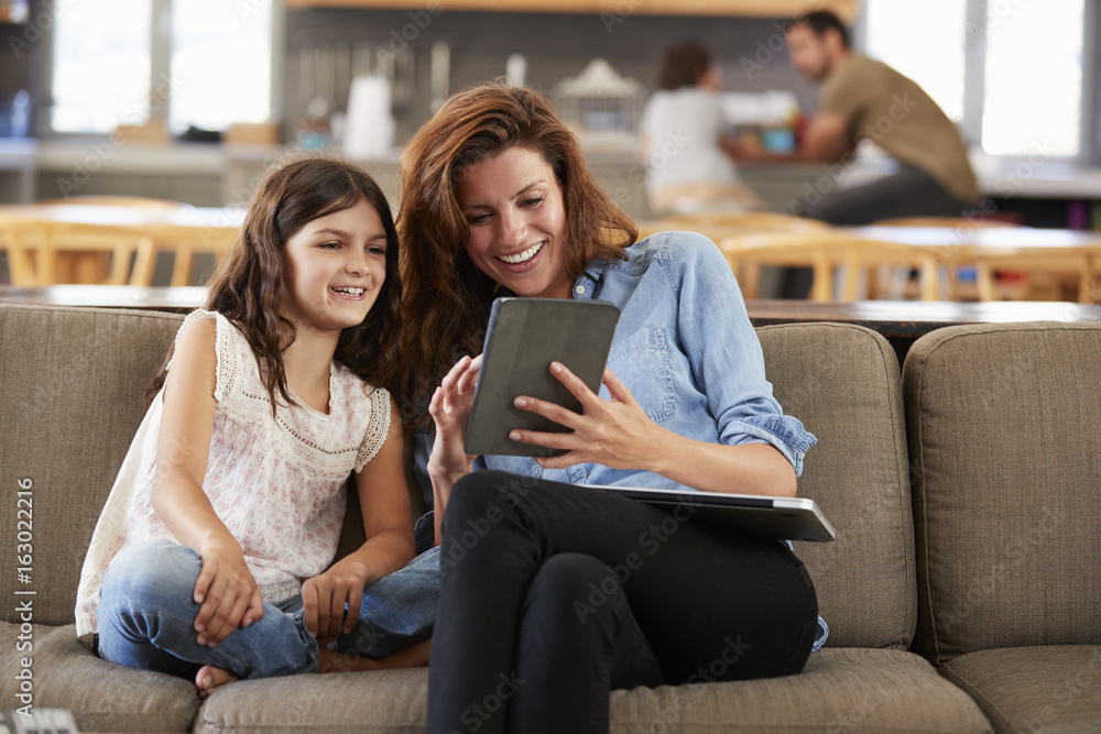 Mother And Daughter Sitting On Lounge Sofa Using Digital Devices Mother And Daughter Sitting On Lounge Sofa Using Digital Devices