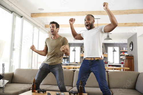 Two Excited Male Friends Celebrate Watching Sports On Television