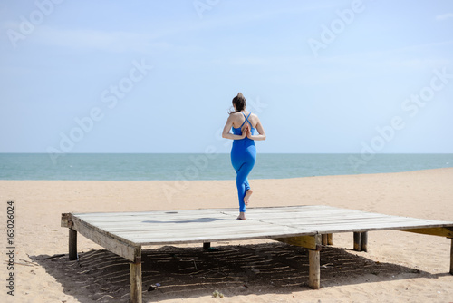 Back view of woman sport stretching over the blue sea outdoor sunny background