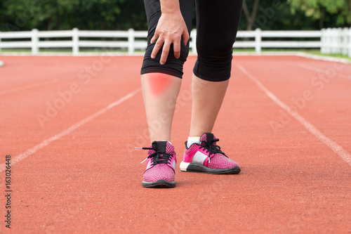 Middle aged woman runner knee pain during training outdoors.