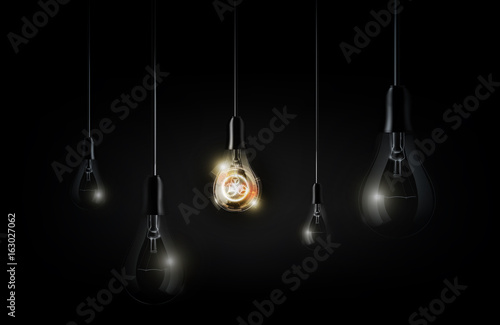 Glowing abstract futuristic light bulb is hanging between a lot of turned off light bulbs on dark black background, vector illustration