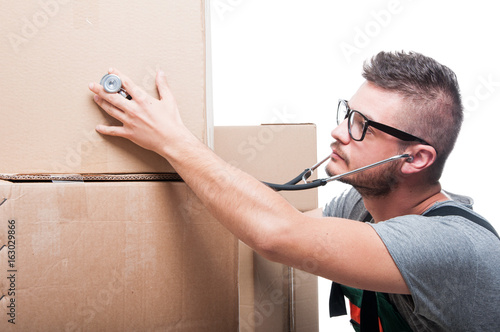 Mover guy checking cardboard box with stethoscope