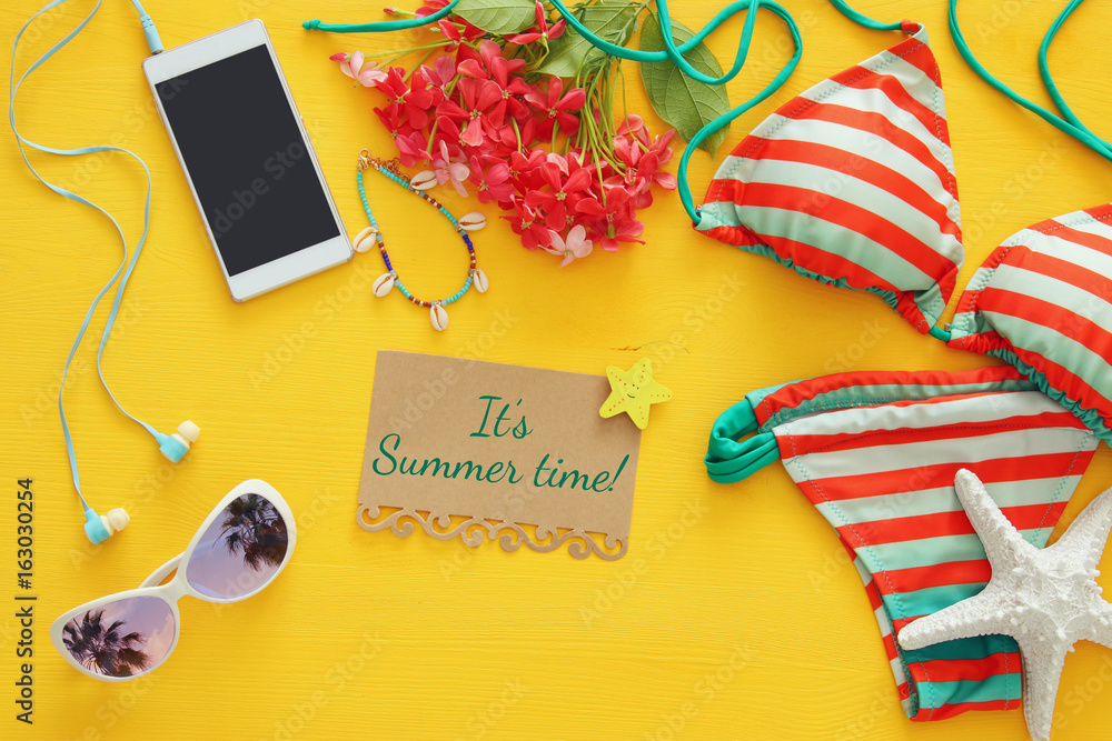 Fototapeta premium Top view of fashion female swimsuit bikini on yellow wooden background