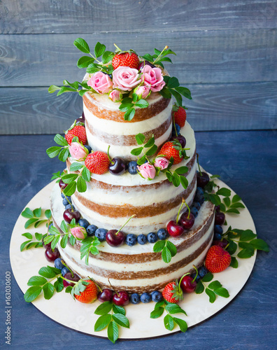 Naked wedding cake decorated with berries and flowers