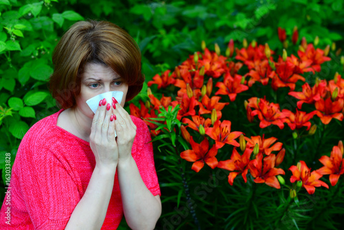woman with an allergic rhinitis near lilies in nature