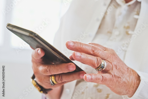 close up image of Senior woman using her mobile phone background.  An idea of modern lifestyle  communication telecommunication connectivity  social networking