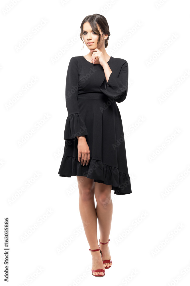 Seductive young latin woman in black flounce dress with hand on chin. Full body length portrait isolated on white studio background. Seductive young latin woman in black flounce dress with hand on chin. Full body length portrait isolated on white studio background.