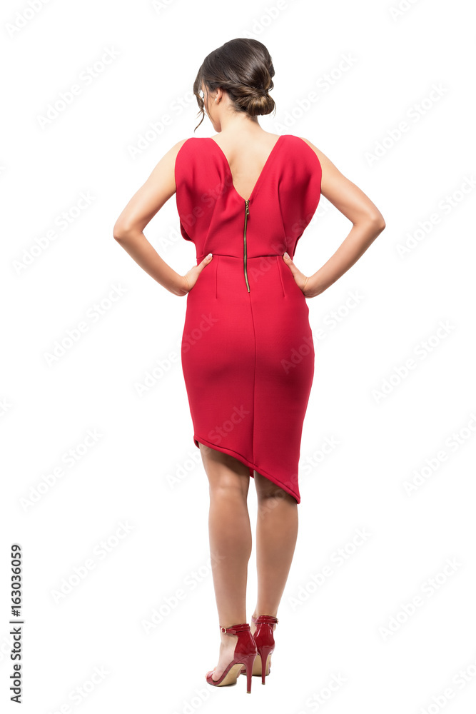 Back view of elegant woman in red evening dress with hands on hips