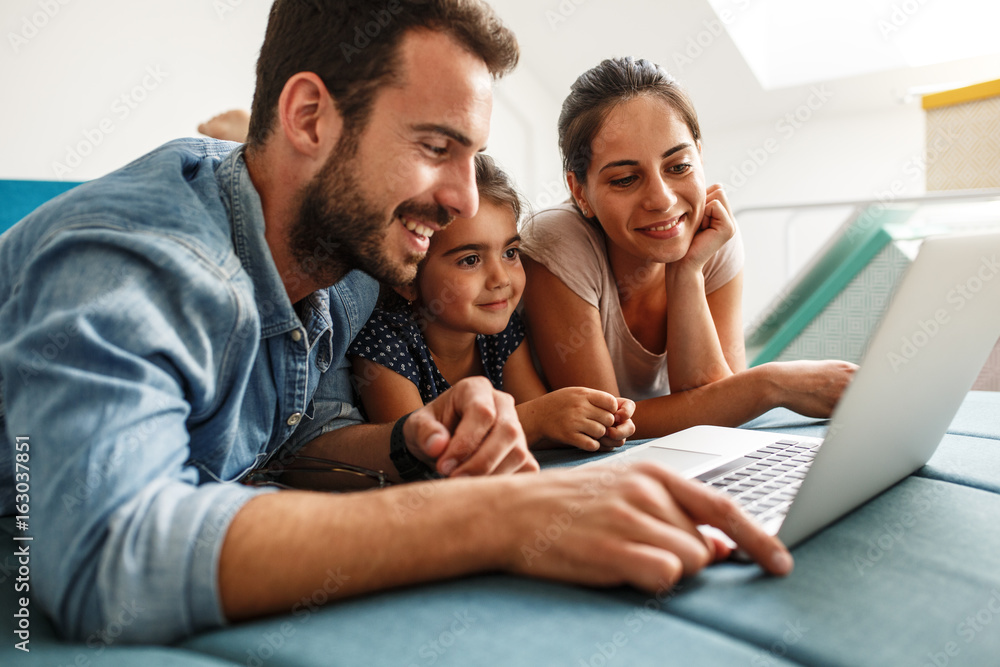 Happy family lies on bed and watching something on laptop. Happy family lies on bed and watching something on laptop.