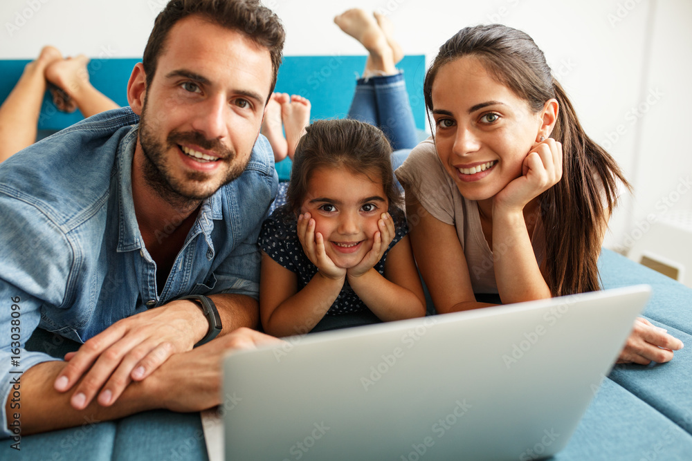Happy family lies on bed and watching something on laptop. Happy family lies on bed and watching something on laptop.