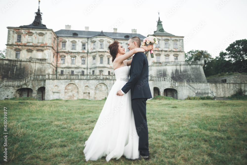Obraz premium Just married poses and kissing with an old fortress on the background