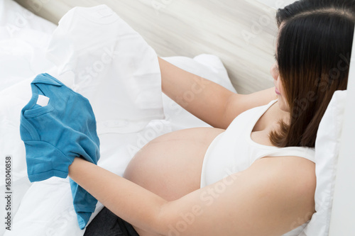 Pregnant woman choosing newborn clothes