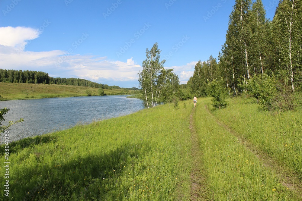 A barely noticeable path along the shore of the lake along which a girl is walking in the distance. A barely noticeable path along the shore of the lake along which a girl is walking in the distance.