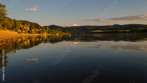 summer beach sunset. beauty sunset by river in summertime. reflection of clouds on water in sunset