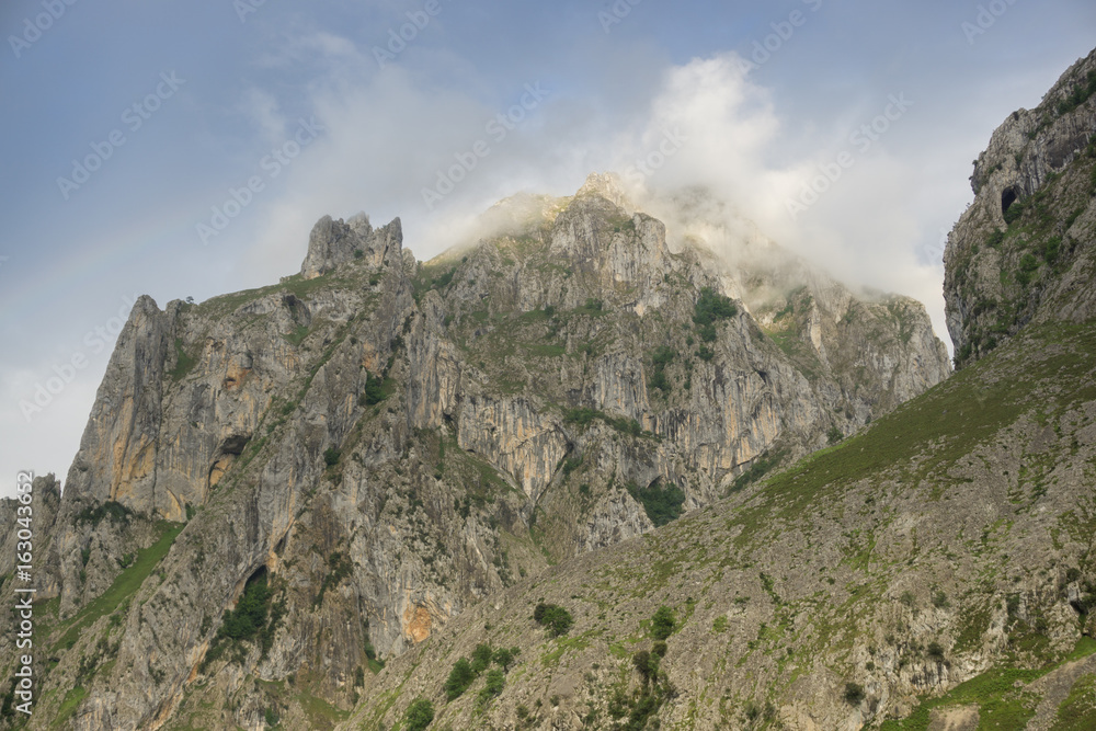 Obraz premium Beautiful landscape of the mountains in Picos de Europa in Spain; hiking trail in foggy and cloudy summer day