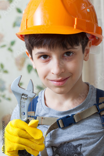 Boy in a protective helmet and with a wrenc photo